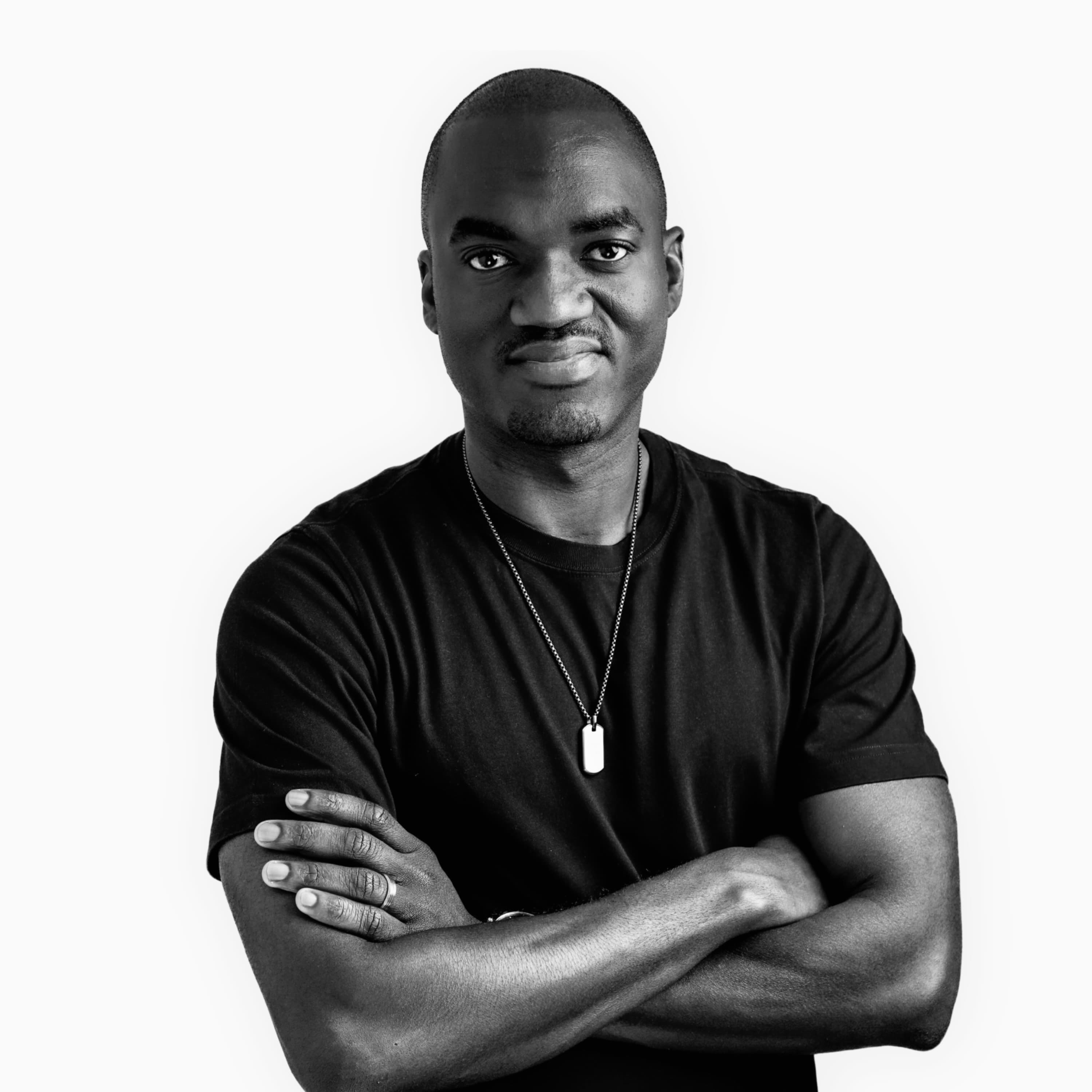 Black-and-white portrait of Tunde Cole, arms folded, wearing a dark shirt